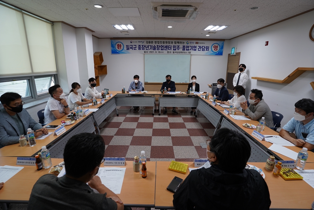 김용문 창업진흥원장이 칠곡군 중장년기술창업센터 입주.졸업기업 간담회 플랭카드 앞에서 간담회를 나누고 있다