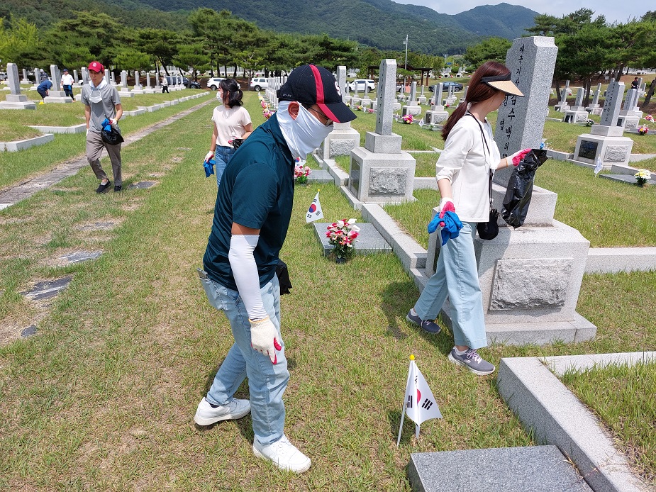 창업진흥원 임직원이 국립대전현충원 묘역 정화활동에 참여하여 비닐을 들고 쓰레기를 찾는 모습의 사진