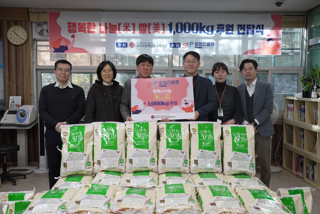 김용문 창업진흥원장과 복지관 직원들이 후원되는 쌀과 함께 사진을 찍고 있음.